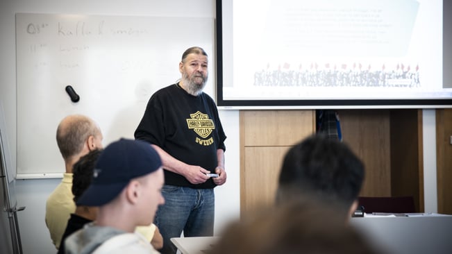 Person som håller i en kurs i en kurslokal och som står framför en tavla